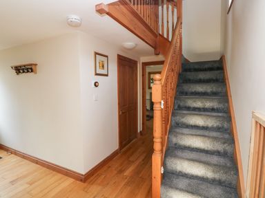 A hallway with wooden floor and carpeted stairs and wooden doors at Ty Melyn in Boncath