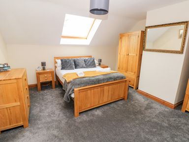 A bedroom with a wooden bed dresser wardrobe bedside tables and a skylight at Ty Melyn in Boncath