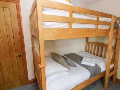 A wooden bunk bed with pillows and folded towels in a room at Ty Melyn in Boncath
