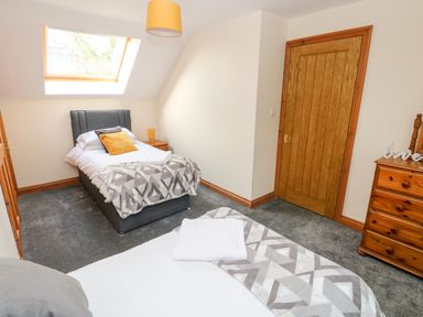 A bedroom with two single beds a wooden door a chest of drawers and a skylight at Ty Melyn in Boncath