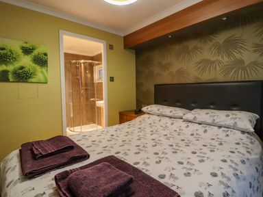 A bedroom with a bed and a view into an ensuite bathroom at Swinsty Lodge in Fewston near Darley