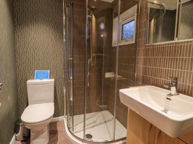 A bathroom with a toilet a corner shower enclosure and a sink at Swinsty Lodge Fewston near Darley