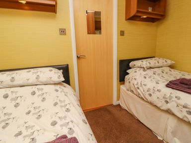 A small bedroom with two single beds and a wooden door at Swinsty Lodge in Fewston near Darley