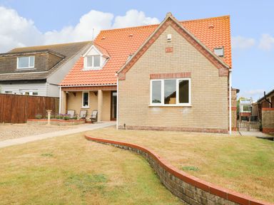 A front view of a brick house with a tiled roof and a lawn at Drifters in Winterton-On-Sea