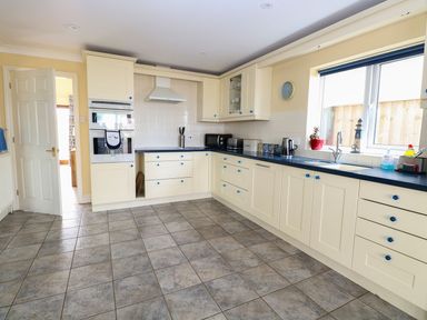 A kitchen with cream cabinets blue countertops tiled floor and a window at Drifters in Winterton-On-Sea