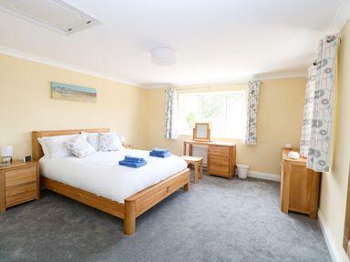 A bedroom with a double bed bedside tables a dressing table and chest of drawers at Drifters Winterton-On-Sea