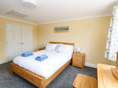 A bedroom with a wooden bed and bedside tables a double door wardrobe and a wooden dressing table at Drifters in Winterton-On-Sea