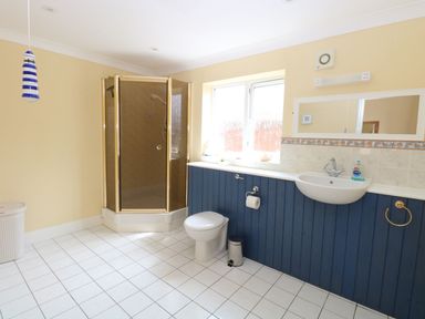 A bathroom with a shower cabin toilet sink mirror and window at Drifters in Winterton-On-Sea