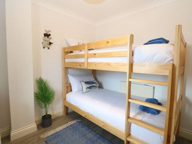 A bedroom with wooden bunk beds a small plant a blue rug and animal wall decoration at Drifters in Winterton-On-Sea