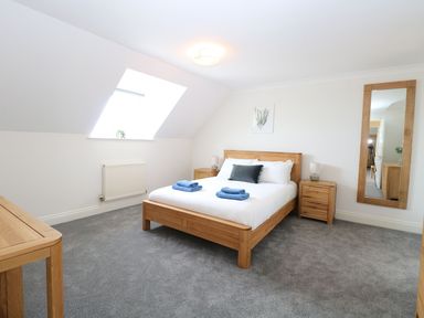A bedroom with a wooden bed and side tables a wall mirror and a skylight window at Drifters in Winterton-On-Sea