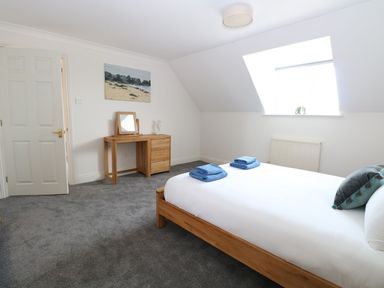 A bedroom with a wooden bed and desk a painting on the wall at Drifters in Winterton-On-Sea