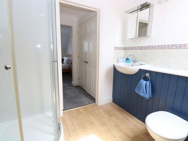 A bathroom with a shower enclosure sink with mirror and towel rail next to door leading to bedroom at Drifters Winterton-On-Sea