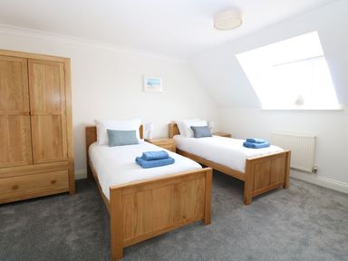 A bedroom with two single beds bedside tables wooden wardrobe and a window at Drifters Winterton-On-Sea