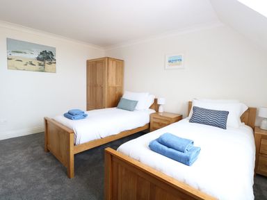 A bedroom with two single beds blue towels wooden furniture and beach pictures at Drifters in Winterton-On-Sea