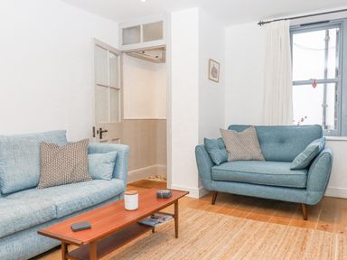 A living room with blue sofas a wooden coffee table and a window at The Cottage on The Square in Chagford