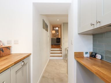 A narrow hallway with steps leading to a living room with a lamp and a sofa at The Cottage on The Square in Chagford