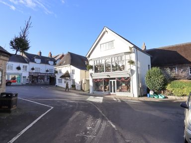 A street view with shops a pedestrian and parked vehicles at The Cottage on The Square in Chagford