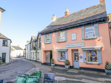 A street view with buildings including the Three Hares Gallery with blue shutters at The Cottage on The Square in Chagford