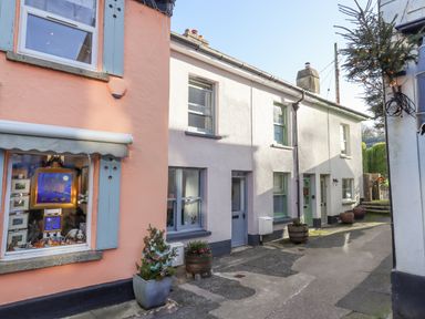 A narrow street with pastel colored houses and potted plants outside at The Cottage on The Square in Chagford