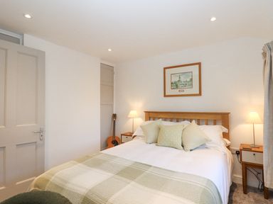 A bedroom with a bed pillows bedside tables lamps a guitar and framed picture at The Cottage on The Square in Chagford