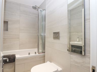 A bathroom with a bathtub shower combination a toilet and a sink with a mirror at The Cottage on The Square in Chagford