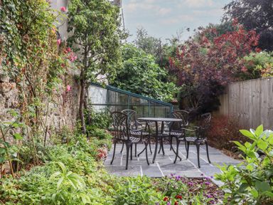 A garden with a table and chairs and a greenhouse at The Cottage on The Square in Chagford