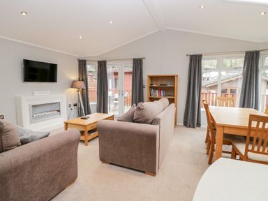 A living room with a sofa coffee table bookshelf dining table and chairs at Highfield Lodge Kirkstone 30 Limefitt Park near Troutbeck