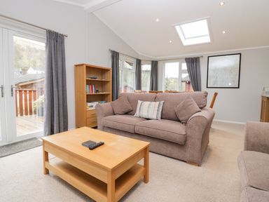 A living room with a sofa coffee table bookshelf and dining table at Highfield Lodge in Kirkstone 30 Limefitt Park near Troutbeck