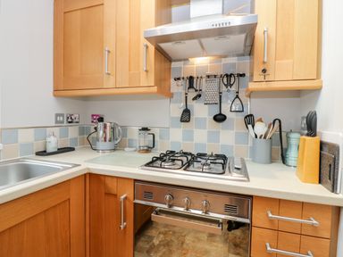 A kitchen corner with a gas stove oven wooden cabinets and kitchen utensils at Highfield Lodge Kirkstone 30 Limefitt Park near Troutbeck