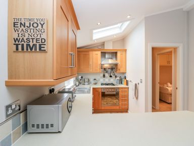 A kitchen with wooden cabinets a microwave an oven and a skylight at Highfield Lodge Kirkstone 30 Limefitt Park near Troutbeck