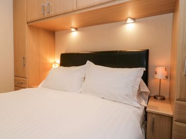 A bedroom with a double bed white bedding bedside tables and lamps at Highfield Lodge Kirkstone 30 Limefitt Park near Troutbeck