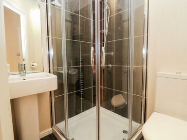 A bathroom with a shower enclosure a pedestal sink and a toilet at Highfield Lodge Kirkstone 30 Limefitt Park near Troutbeck