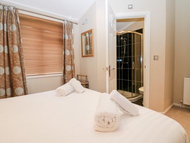 A bedroom with a bed and towels and an open door showing a shower at Highfield Lodge Kirkstone 30 Limefitt Park near Troutbeck