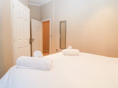 A bedroom with a bed with white towels on and two open doors at Highfield Lodge in Kirkstone 30 Limefitt Park near Troutbeck