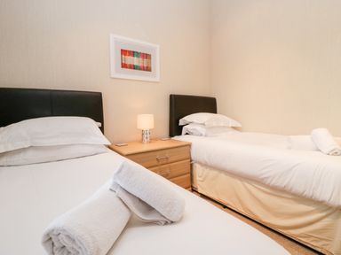 A bedroom with two single beds a wooden nightstand and a lamp at Highfield Lodge Kirkstone 30 Limefitt Park near Troutbeck