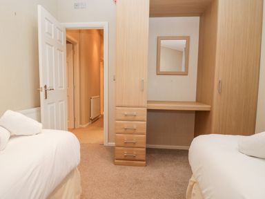 A bedroom with two single beds towels on each bed a wooden wardrobe with drawers and a mirror at Highfield Lodge Kirkstone 30 Limefitt Park near Troutbeck