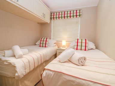 A bedroom with two single beds and a nightstand with a lamp at Highfield Lodge Kirkstone 30 Limefitt Park near Troutbeck