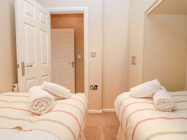 A bedroom with two beds each having rolled white towels at Highfield Lodge Kirkstone 30 Limefitt Park near Troutbeck