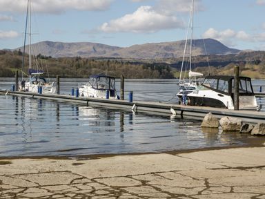 A marina with boats docked along a pier on a lake with mountains in the background at Highfield Lodge in Kirkstone 30 Limefitt Park near Troutbeck
