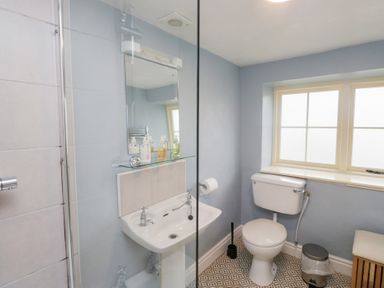 A bathroom with a toilet sink mirror and window at Latch Cottage in Keswick