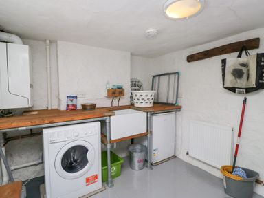 A utility room with a washing machine a sink a mini fridge a mop and bucket and a laundry basket at Latch Cottage in Keswick
