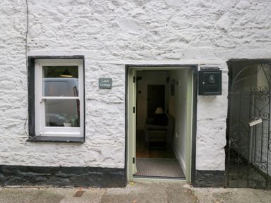 The entrance of a white stone cottage with a window a door and a black mailbox at Latch Cottage in Keswick