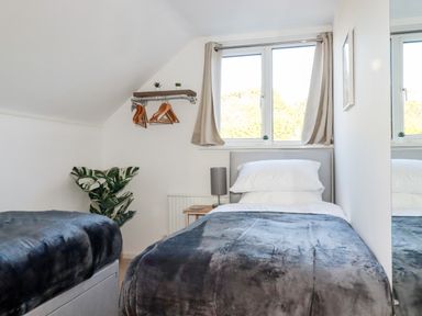 A bedroom with two beds a window and a small shelf with hangers at Seacroft in Crantock