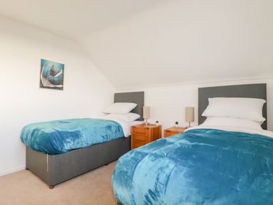 A bedroom with two single beds blue blankets bedside tables and lamps at Seacroft in Crantock