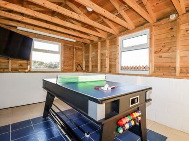 A recreational room with a combination pool and table tennis table and a wall-mounted television at Seacroft in Crantock