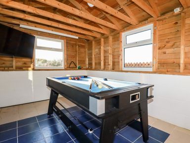 A game room with a pool table two windows and a wall mounted television at Seacroft in Crantock