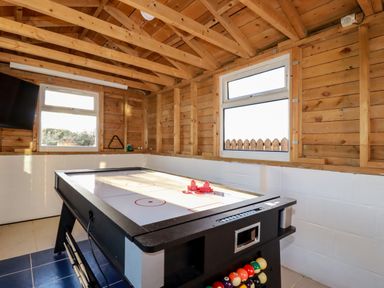 A game room with an air hockey table and a pool cue rack in a wooden room at Seacroft in Crantock