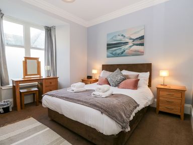 A bedroom with a bed and bedside tables with lamps and a dressing table with mirror at Carlton House Apartment 1 in Keswick