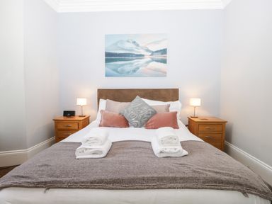 A bedroom with a bed and bedside tables with lamps at Carlton House Apartment 1 in Keswick