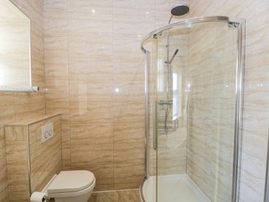 A bathroom with a toilet and a glass enclosed corner shower at Carlton House Apartment 1 in Keswick